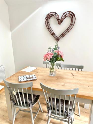 a dining room table with a heart hanging on the wall at Wayside, Yorkshire Wolds Holiday Home in Nafferton