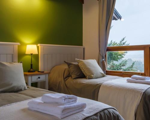 2 camas en una habitación con paredes verdes y ventana en Oliver Mountain Home Green en San Martín de los Andes