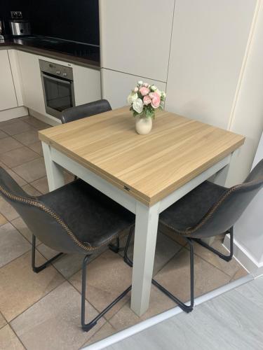 einen Holztisch mit zwei Stühlen und eine Vase mit Blumen in der Unterkunft Wharf Inn Premier Apartment Central Manchester - Free Private Parking in Manchester