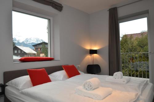 Un dormitorio con una cama blanca con sillas rojas y una ventana en Apartmenthouse "5 Seasons" - Zell am See, en Zell am See