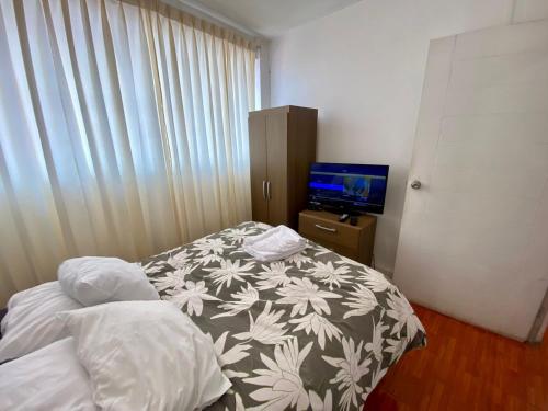 a small bedroom with a bed and a television at A COZY APARTMENT IN CENTRAL CUSCO in Cusco