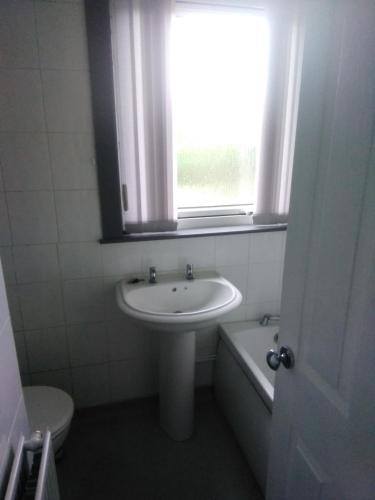 a bathroom with a sink and a toilet and a window at Room 2 in Broxburn