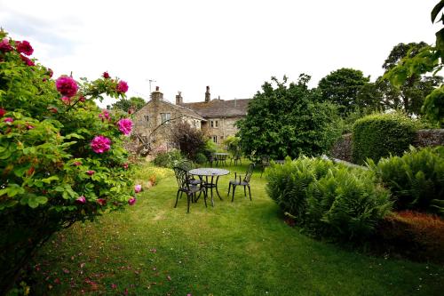 a garden with a table and chairs and flowers at Ashfield House in Grassington