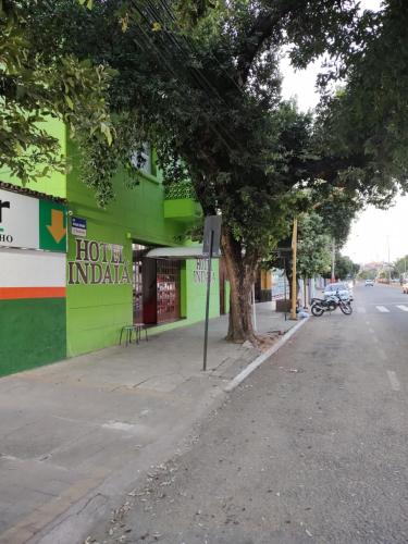 un edificio con un árbol al lado de una calle en Hotel Indaiá, en Governador Valadares
