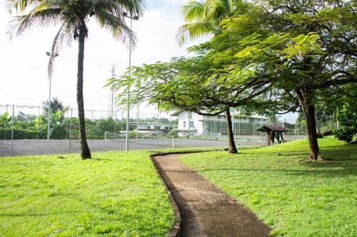 a path through a park with palm trees at Le Jardin Privé, appartement standing, piscine, terrasse, jardin, parking privé in Cayenne