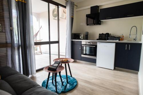 uma cozinha com um sofá e uma mesa num quarto em Le Privilège appartement standing, piscine, terrasse, jardin, parking privé em Cayenne