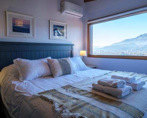 a bedroom with a large bed with towels on it at Oliver Mountain Home Cabin in San Martín de los Andes
