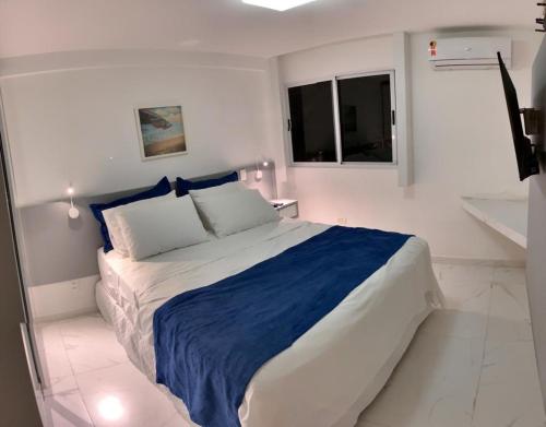 una camera bianca con un grande letto con una coperta blu di Pé na areia - Muro Alto - Porto de Galinhas a Porto De Galinhas