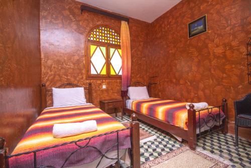 una camera con due letti e una finestra di Hotel TOURAGHINE a Chefchaouen