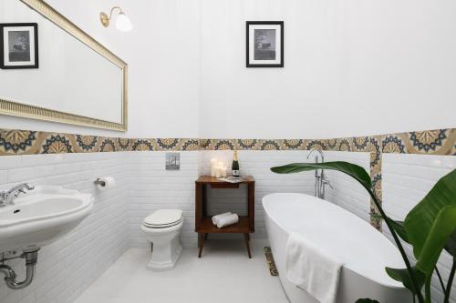 La salle de bains est pourvue d'un lavabo, d'une baignoire et de toilettes. dans l'établissement oompH Koszyki Luxurious Apartments, à Varsovie