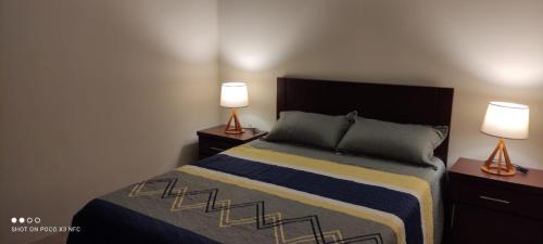 a bedroom with a bed and two lamps on tables at Departamento El-Shaddai in Tarija