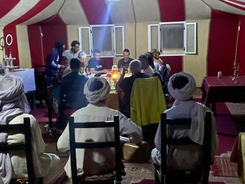 a group of people sitting in chairs in a room at Merzouga Paradise Luxury Camp in Merzouga