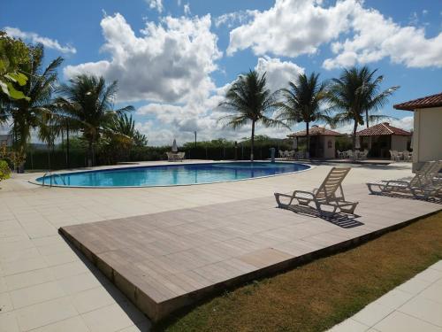 einen Pool mit 2 Liegestühlen und Palmen in der Unterkunft Casa com 3 quartos em Condomínio de Luxo in Gravatá