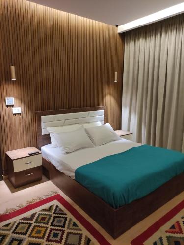 a bedroom with a large bed with a wooden wall at Luxury Stay in Sheikh Zayed