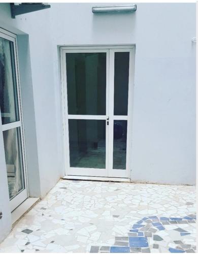 une porte ouverte sur un bâtiment blanc avec du carrelage. dans l'établissement JADO House, à Dakar