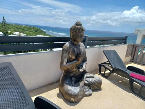 a statue of a woman sitting on a balcony overlooking the ocean at Villa vue mer 180°, piscine in Saint-François