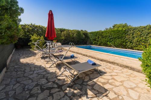 a pool with two lounge chairs and a red umbrella at FINCA SA SINI in Búger