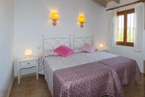 a bedroom with a bed with pink pillows on it at FINCA SA SINI in Búger