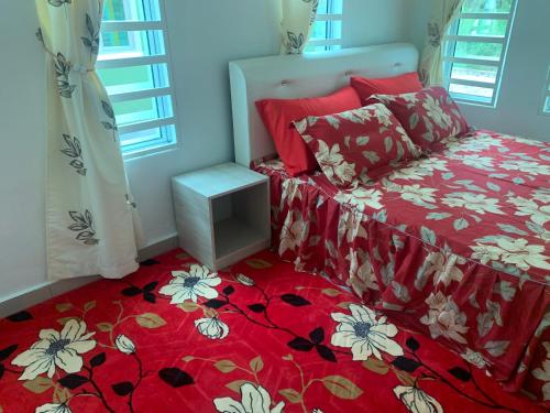a bedroom with a bed with a red and white comforter at Damai Homestay in Kampong Jabi