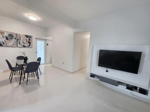 a living room with a television and a table with chairs at Home San Juan in San Juan