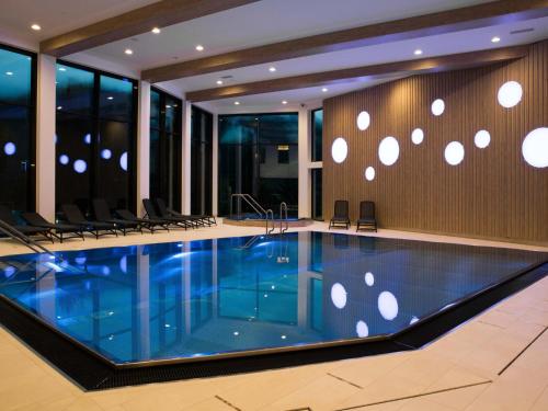 a swimming pool in a building with chairs around it at Matrei Park 90 in Klaunz