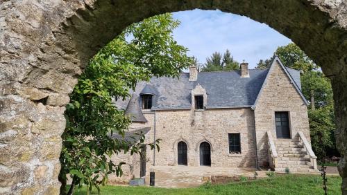 una vieja casa de piedra vista a través de un arco en Le Manoir de Menglieu, en Treffléan