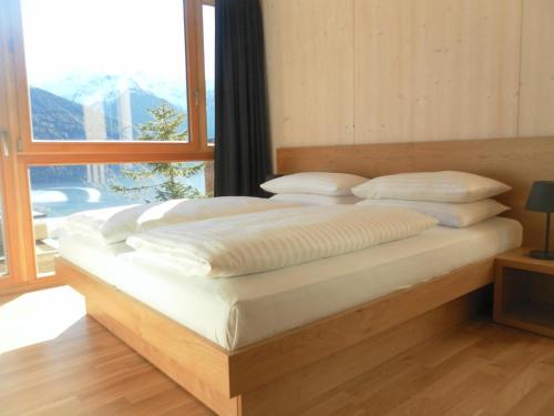 uma cama num quarto com uma grande janela em Chalet Klassik em Kals am Grossglockner