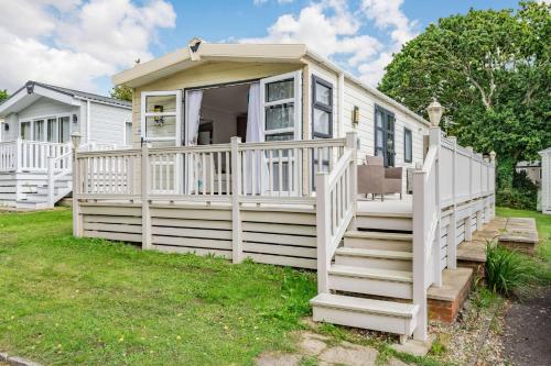 a white tiny house with a porch and stairs at Skyline Lodge in Lymington