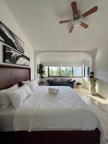 a bedroom with a white bed with a ceiling fan at Dream penthouse with private rooftop and amazing views in Cancún