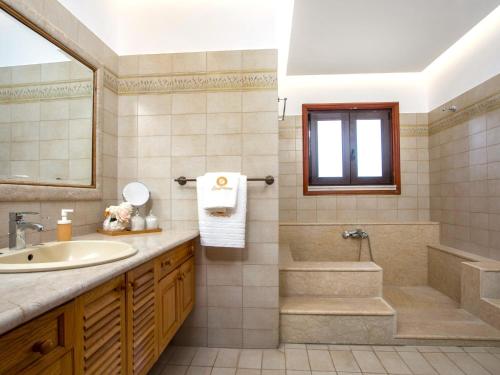 une salle de bain avec un lavabo, une baignoire et une douche dans l'établissement Holiday Home near Beach in Afandou, à Koskinou