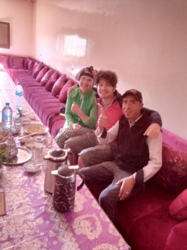 a group of people sitting on a purple couch at Maison D'hôtes Chez Bassou Agoudal in Agoudal