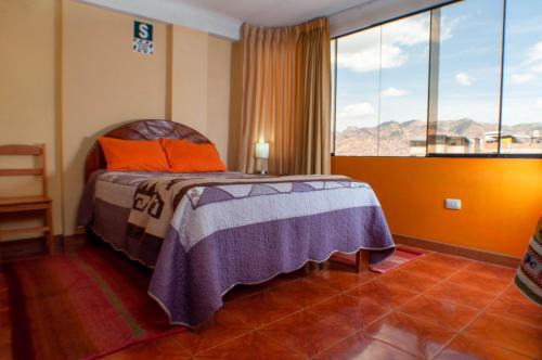 a bedroom with a bed and a large window at T'ika Guest House in Cusco