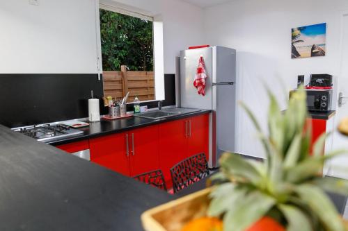 a kitchen with red cabinets and a stainless steel refrigerator at Domaine de Sainval in Sainte-Rose