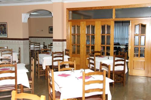 a dining room with white tables and wooden chairs at Hostal Restaurante La Masía in Villareal
