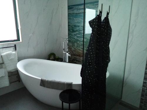 a bathroom with a bath tub and an umbrella on the wall at Two rooms with one queen size bed in each room one bathroom for the two rooms in Mount Maunganui