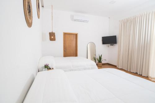 two beds in a white room with a tv at Equinoccio Hotel in Santa Ana