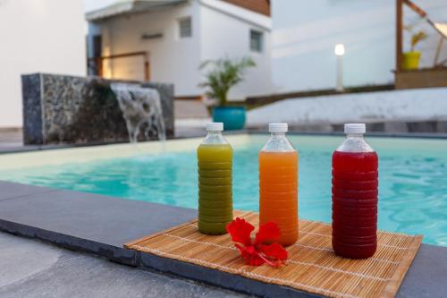 three bottles of juice sitting next to a swimming pool at Domaine de Sainval in Sainte-Rose