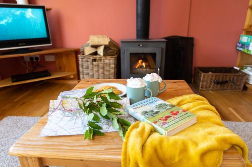 a living room with a coffee table with a book and a fireplace at The Story House Cottage - Mendips Countryside near Axbridge in Axbridge
