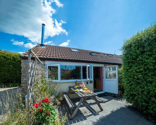 a small house with a picnic table in front of it at The Story House Cottage - Mendips Countryside near Axbridge in Axbridge