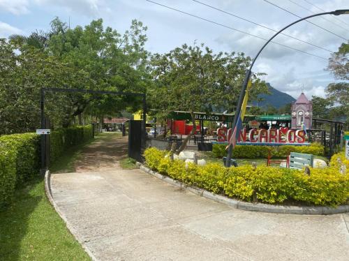 a sidewalk in a park with a fence and flowers at Hotel Selva Cristal in San Carlos