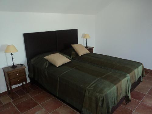 a bedroom with a large green bed with two night stands at Casas da Moagem in São Domingos
