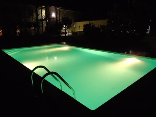 an empty swimming pool at night with green illumination at Casas da Moagem in São Domingos