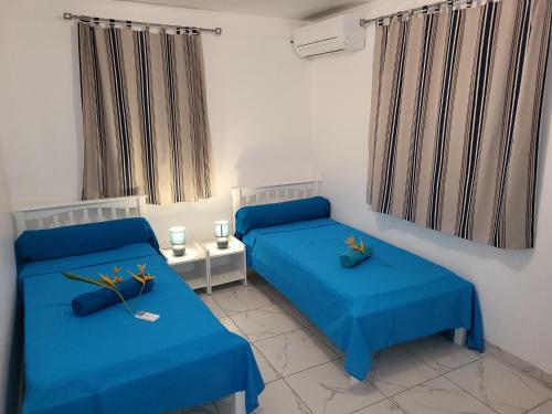 2 Betten in einem Zimmer mit blauer Bettwäsche in der Unterkunft Maison Indép, Spa, Mer, Jardin, Bien-être in Les Trois-Îlets