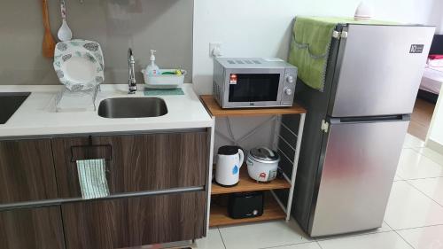 a small kitchen with a refrigerator and a microwave at New Modern Condo with Pool at Bangi in Kampong Tangkas