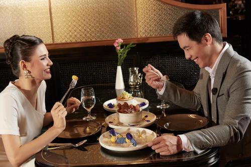 a man and woman sitting at a table eating food at Crowne Plaza Vientiane by IHG in Vientiane