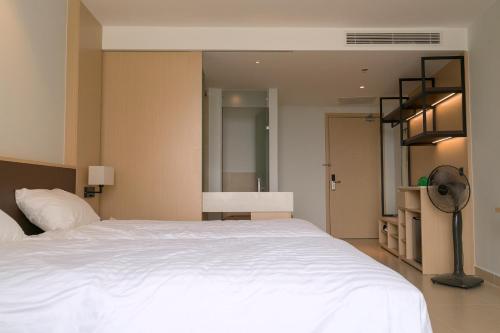 1 dormitorio con 1 cama blanca grande y ventilador en Seaview Arena Cam Ranh Nha Trang hotel near the airport en Cam Ranh