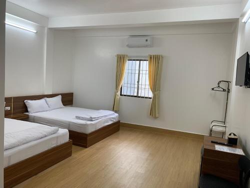 a bedroom with two beds and a window at Nhà Nghỉ 68 Rạch Giá in Rach Gia