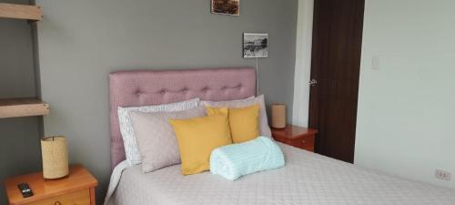 a bedroom with a bed with yellow and blue pillows at Cabaña Bellavista in Iza