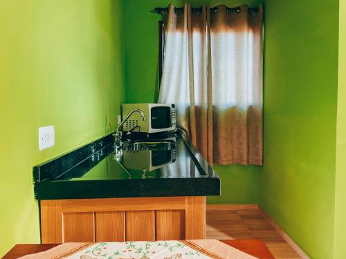 a green bathroom with a sink and a microwave at Recanto do Loriano in Monte Verde