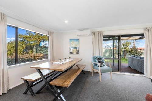 a dining room with a table and a chair and windows at North South Holiday Park in Christchurch